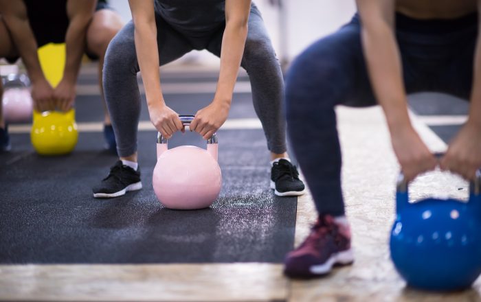 group of healthy young athletes doing exercises with kettlebells at cross fitness studio