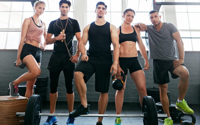 Portrait, personal trainer and group with equipment in gym, confidence and fitness expert for wellness. Join us, low angle and people together for development, pride or coach team for club membership.